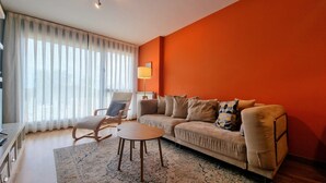 A modern living room with a beige sofa, a wooden coffee table, and a rocking chair. - Apartamento La Muga Azul (Celorio (Llanes))