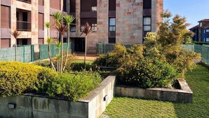 A multi-story building with a courtyard featuring a variety of plants and a small garden area. - Apartamento La Muga Azul (Celorio (Llanes))