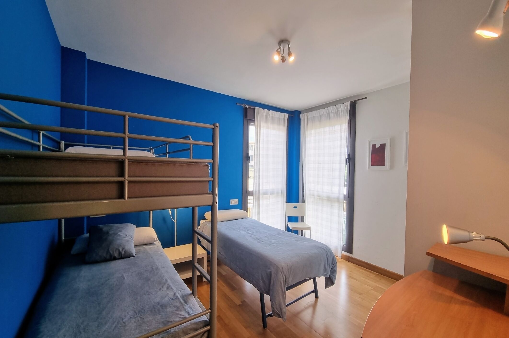 A room with bunk beds, a single bed, a desk, and a chair.