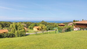 Paisaje rural con casas, cielo despejado y vista al mar.