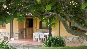 A patio area with a stone floor, a wooden table with chairs, and a potted plant. - [1] (Ovio)
