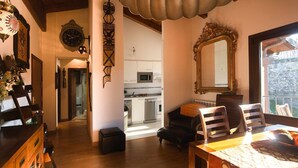 A cozy living room with a wooden dining table, a large mirror, and a view of the kitchen. - Apartamento La Casa Mágica de Llanes (Pancar)