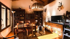 A traditional Japanese-style living room with a wooden dining table, chairs, a TV, and a cabinet with glass doors. - Apartamento La Casa Mágica de Llanes (Pancar)
