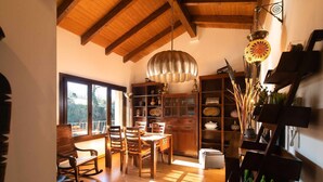 A dining area with wooden furniture, a chandelier, and a view of the outdoors. - Apartamento La Casa Mágica de Llanes (Pancar)