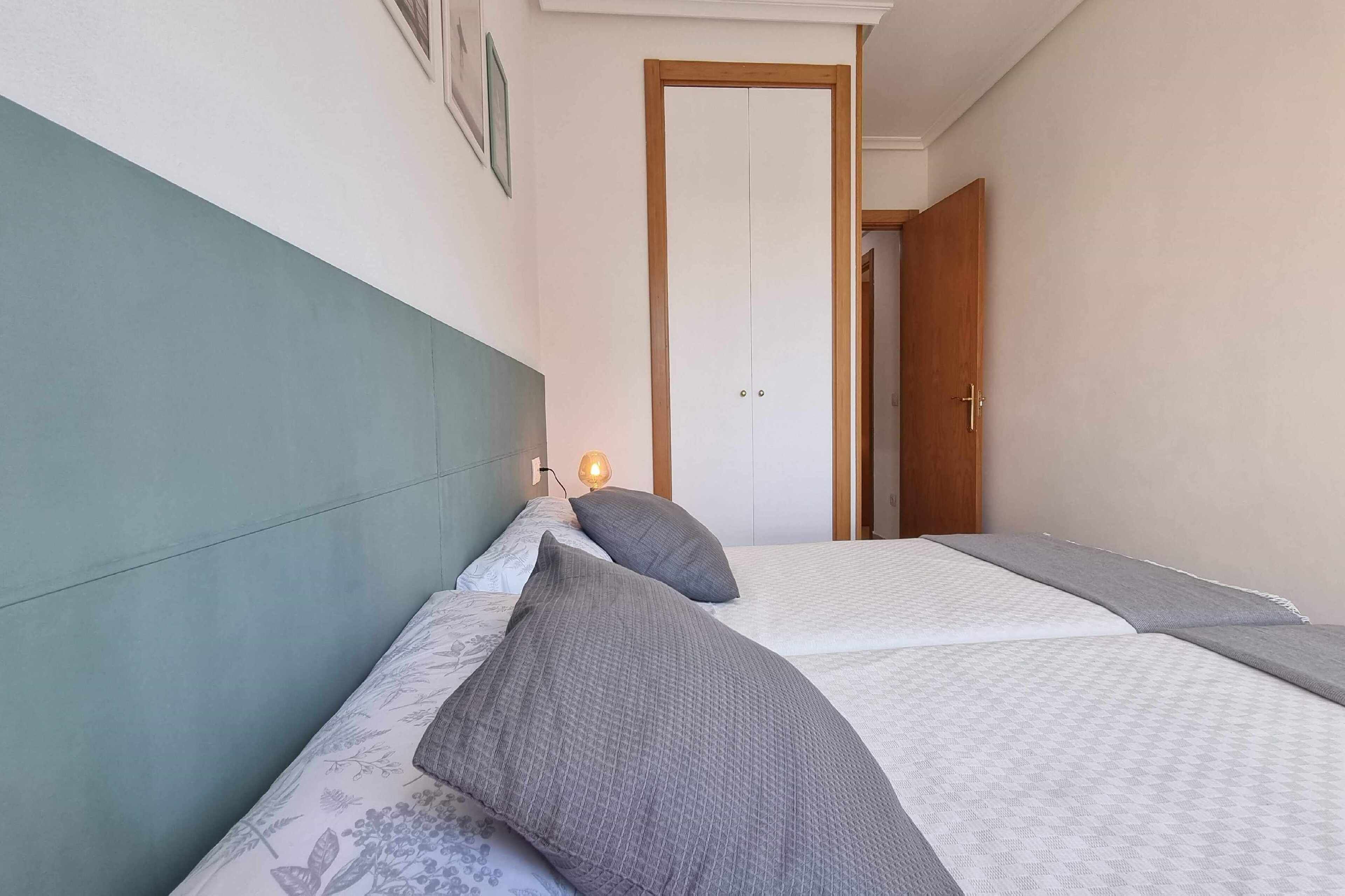 Una camera da letto con due letti, un comodino con una lampada e una porta sullo sfondo.