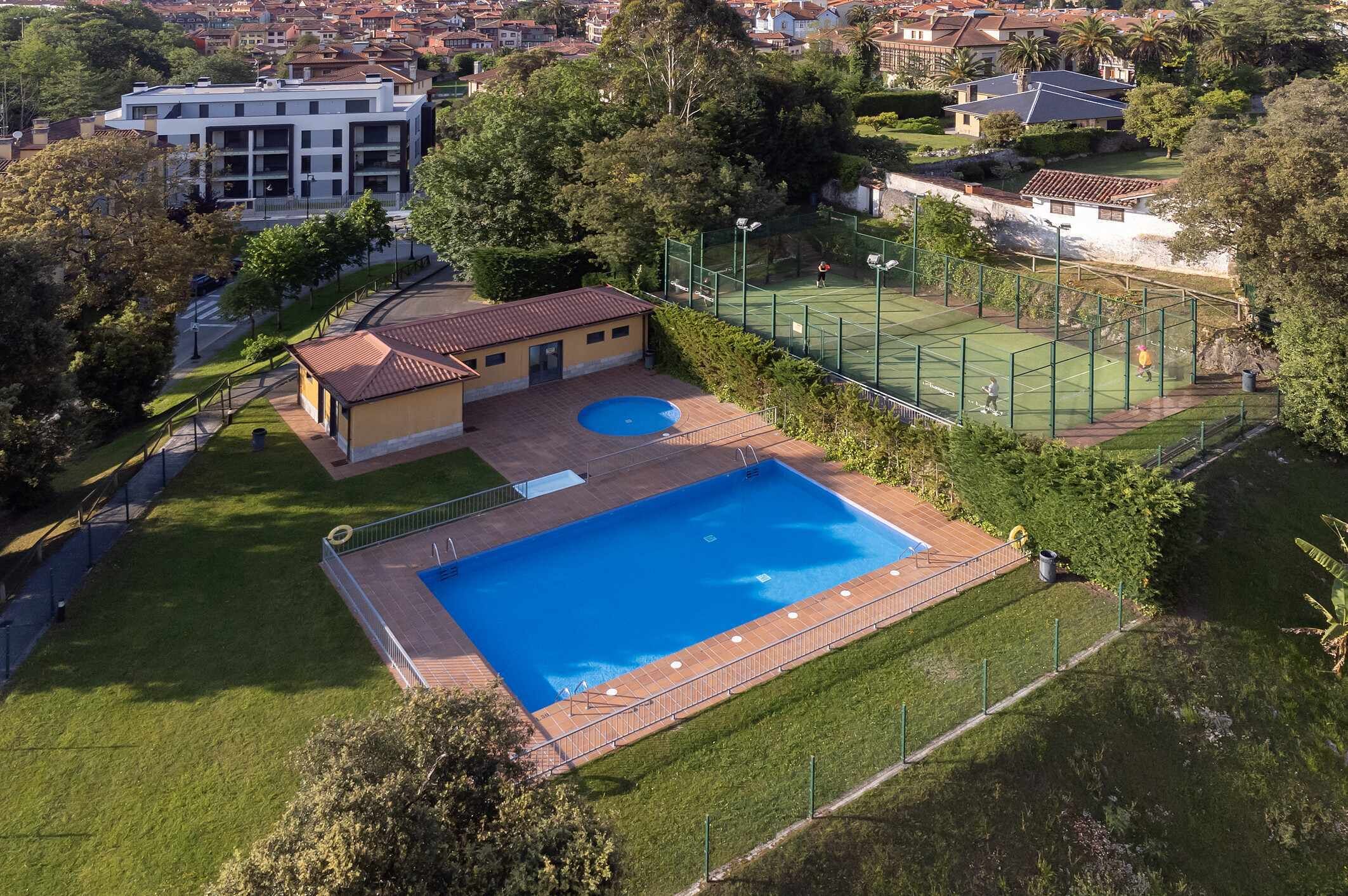 Zona residencial con piscina, cancha de tenis y un pequeño edificio.
