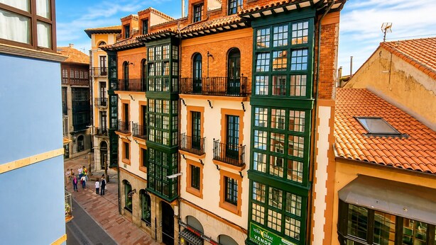 A multi-story building with a traditional architectural style, featuring balconies and large windows. - Apartamento Mercaderes (Llanes)