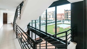 Een modern appartement met een trap naar een balkon met uitzicht op een binnentuin met een zwembad.