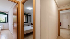 Een slaapkamer met een bed, een raam en een deur naar een andere kamer.