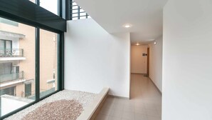 Een modern interieur met een groot raam, een plantenbak gevuld met kiezelstenen en een betegelde vloer.