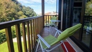Un balcon donnant sur une zone boisée, une table avec des chaises et une porte vitrée.