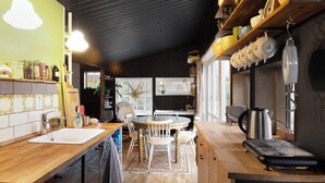 Une cuisine avec un plan de travail en bois, un évier, une table à manger avec des chaises et une bouilloire.