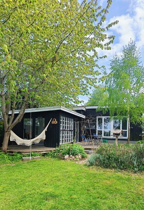 Una casa con hamaca, terraza y jardín.