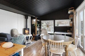 Una sala de estar acogedora con chimenea, una mesa de comedor con sillas, un sofá y una estantería.