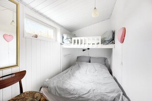 Una habitación con literas, una silla, un ventanal y un espejo.