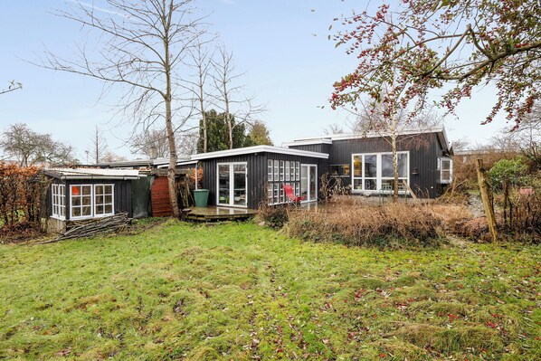 Een modern huis met een terras, een tuinhuisje en een tuin.