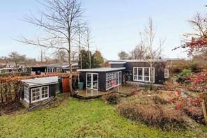 Una casa moderna con un balcón, un pequeño jardín y vistas del entorno.