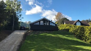 A modern house with a sloped roof, large windows, and a well-maintained lawn. - Cottage in Grønninghoved with view (Sjølund)