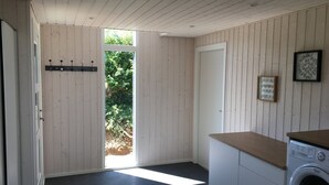 A modern kitchen with a washing machine, a door leading to a garden, and a wall-mounted picture. - Cottage in Grønninghoved with view (Sjølund)