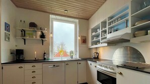 Ett kök med vita skåp, en spis och ett fönster med utsikt.