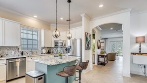 A modern kitchen with a central island, stainless steel appliances, and bar stools.