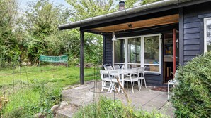 A house with a patio, a table with chairs, and a swing set. - Cottage by Veddinge in charming 70s style (Fårevejle)