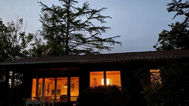 A house with a porch, a dining area with chairs, and a large window. - Cottage by Veddinge in charming 70s style (Fårevejle)