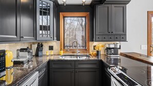 Una cucina moderna con mobili scuri, un lavello in acciaio inox e un forno integrato.