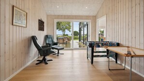 A room with wooden paneling, a billiards table, two chairs, and a view through a glass door. - Lovely, new-built cottage near sea (Aabenraa)