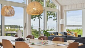 A dining area with a table, chairs, and a view of the outdoors. - Lovely, new-built cottage near sea (Aabenraa)
