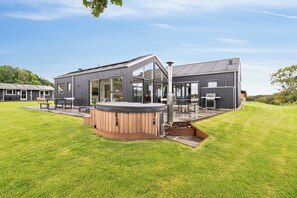 Un bâtiment moderne doté d’un jacuzzi, d’un espace salon extérieur et d’une grande terrasse.