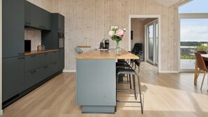 A modern kitchen with a wooden island, black cabinets, and a view to the outside. - Lovely, new-built cottage near sea (Aabenraa)