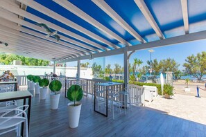 An outdoor patio area with tables and chairs, potted plants, and a view of the sea. - 20m from the beach - garden with parking - furnished terrace - pet friendly (Carovigno)