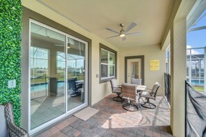 Eine überdachte Terrasse mit Deckenventilator, eine Glastür zum Pool und ein Schild mit Poolregeln.