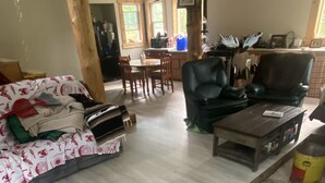 A living room with a sofa, a coffee table, and a dining area with chairs and a table. - Private house on wooded acreage (Talkeetna)