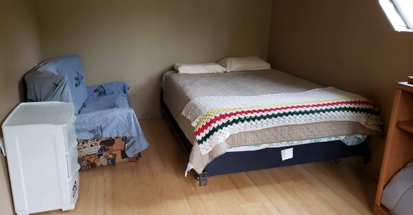 A small, compact room with a bed, a chair, and a desk. - Private house on wooded acreage (Talkeetna)
