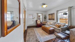 A spacious living room with a large mirror, a sofa set, a coffee table, and a rug.