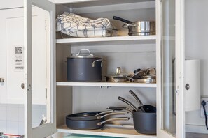 Ein Küchenschrank mit Töpfen, Pfannen und einem zusammengelegten Tuch.