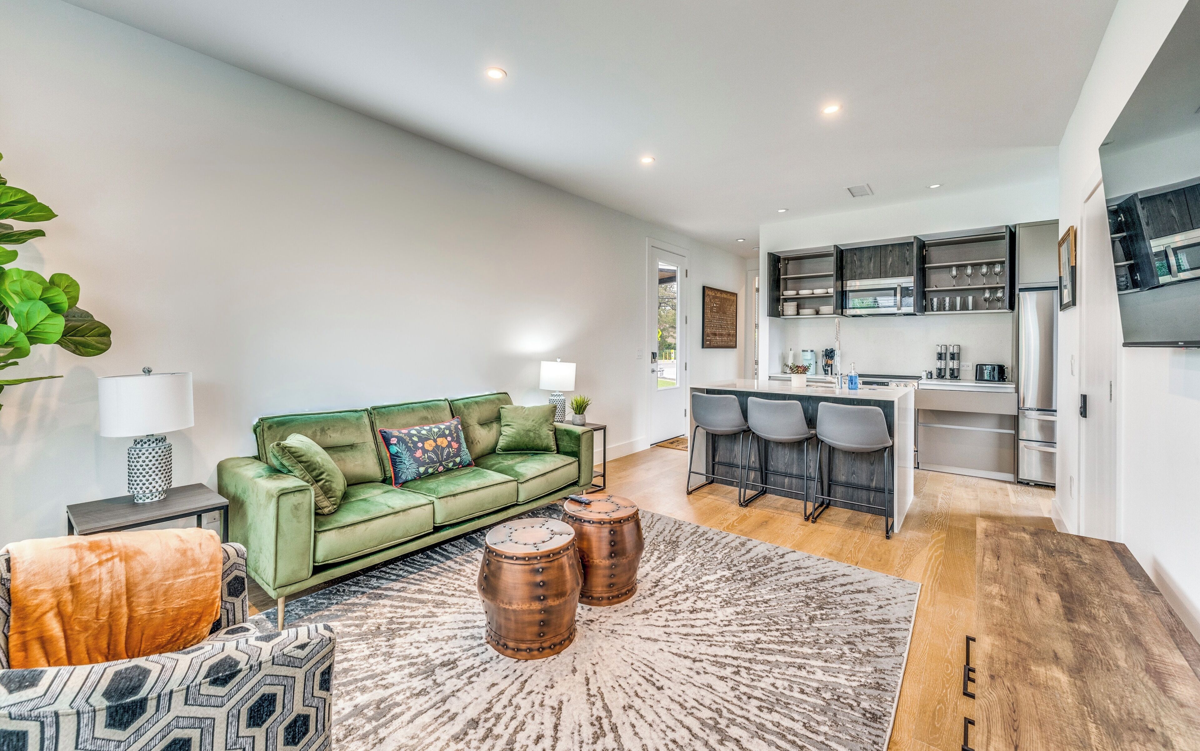 A modern living room with a green sofa, a coffee table, and a patterned rug.