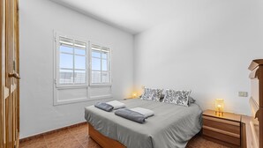 A bedroom with a bed, bedside tables, a window, and a nightstand. - Casa Merlín | Holiday Home in Lanzarote - Spain (Playa Honda)