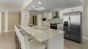 Una cocina moderna con una isla grande, electrodomésticos de acero inoxidable e iluminación empotrada.
