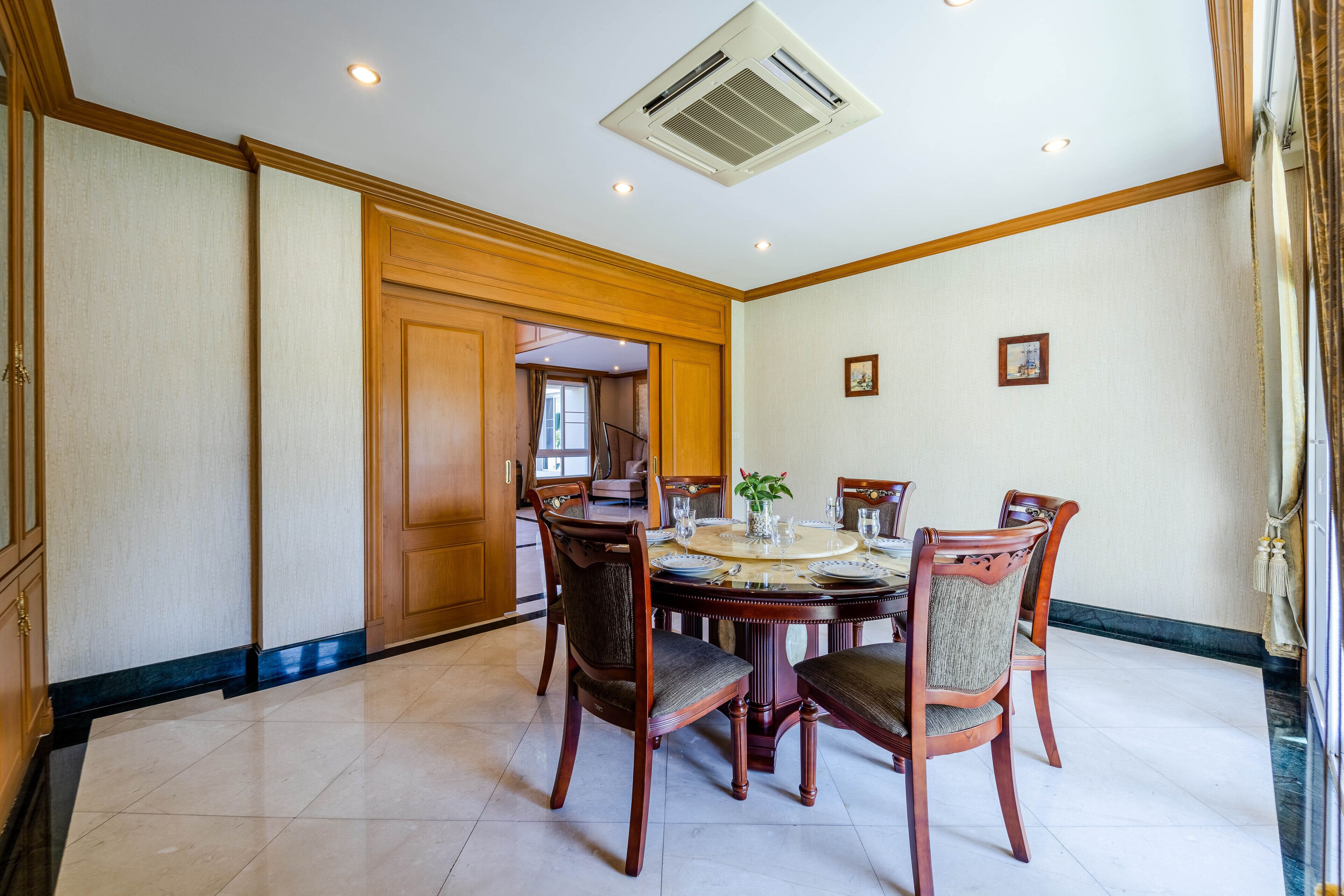 Un comedor con una mesa redonda, cuatro sillas y un aire acondicionado instalado en el techo.