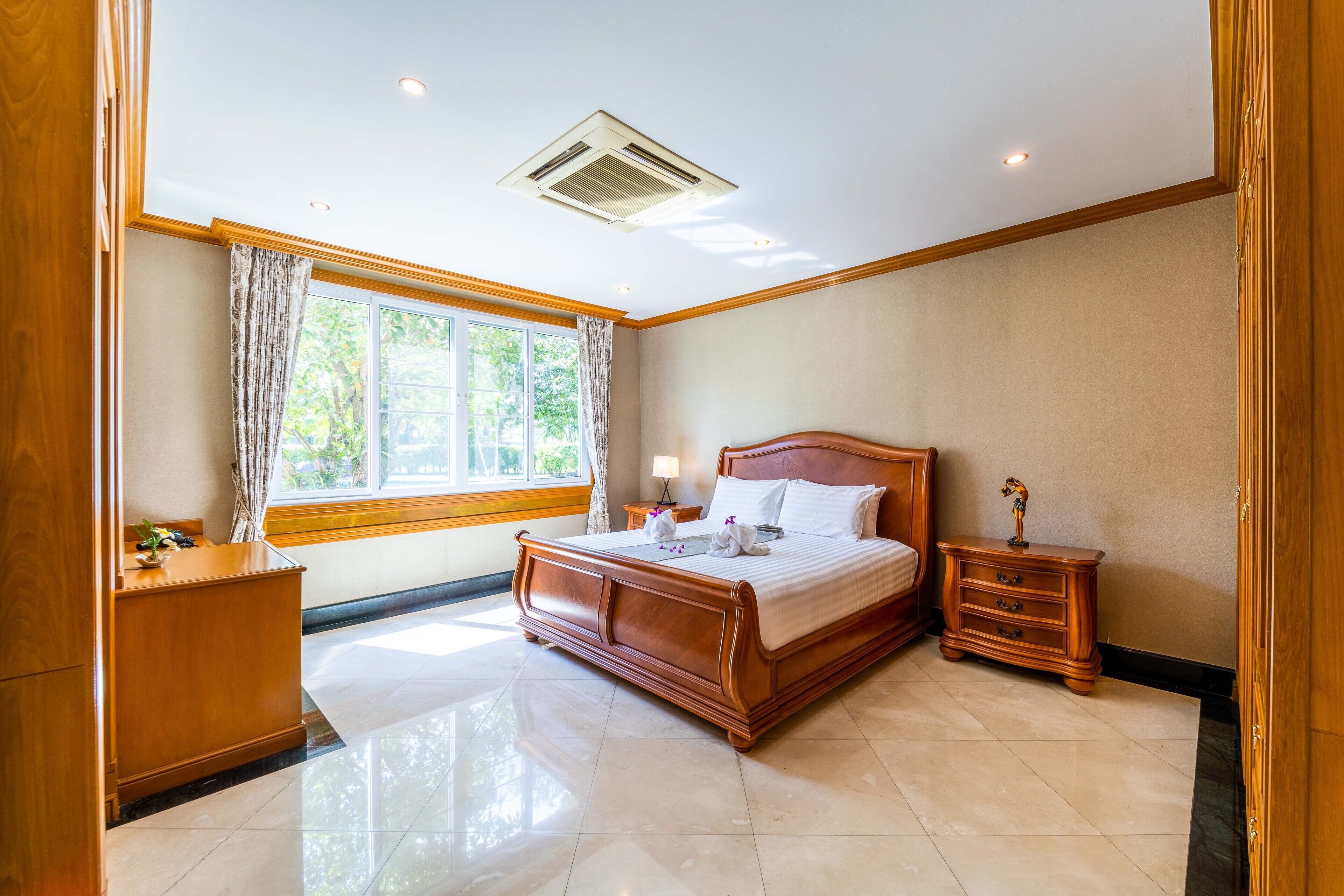 A bedroom with a wooden bed, a nightstand, a dresser, and a window with curtains.