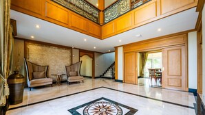 A spacious lobby with a marble floor, a central decorative tile, a staircase, and a dining area. - Luxury 6 Bed Mansion - CAS (Cha-am)