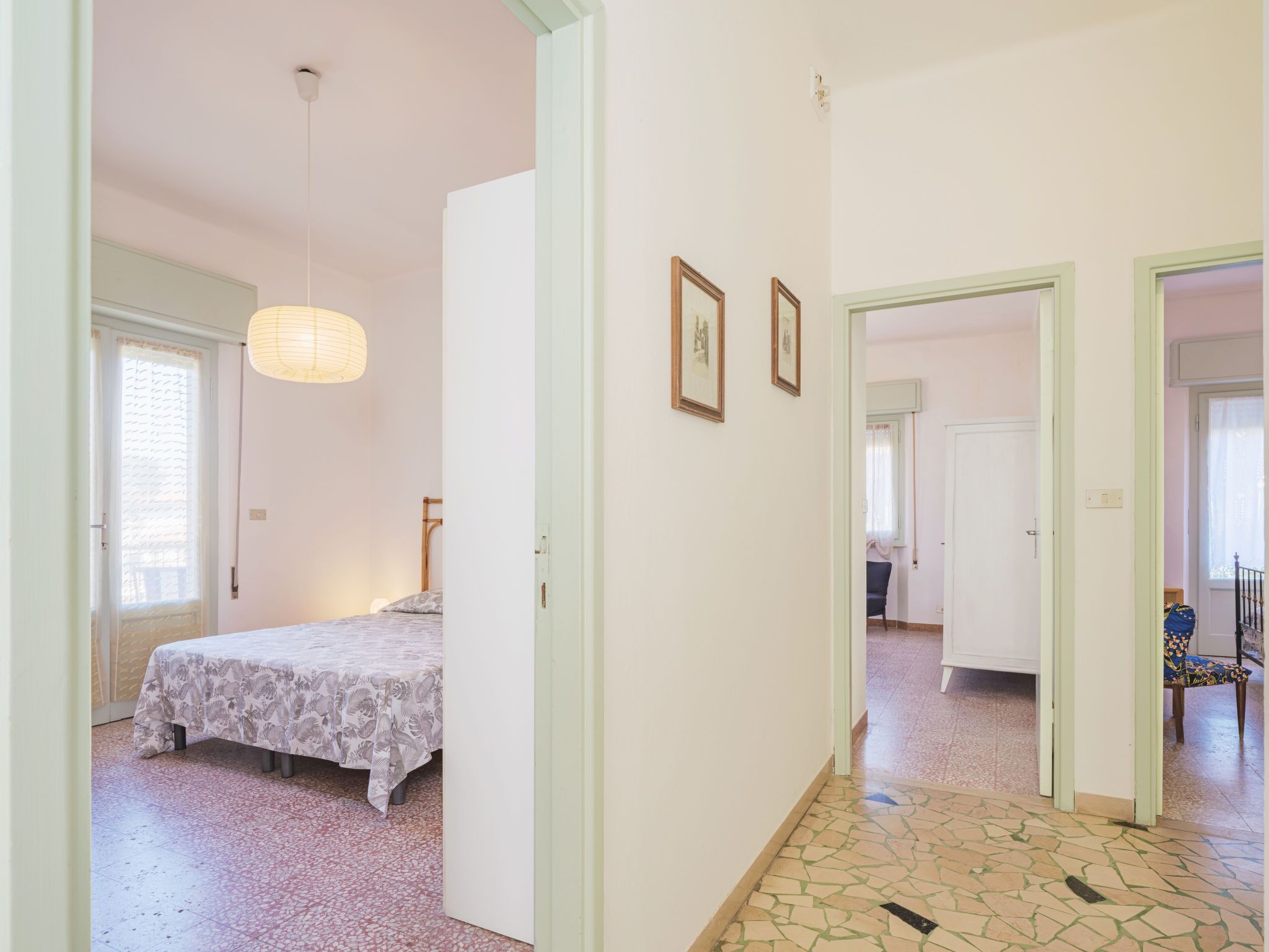Un dormitorio con cama, una mesita de noche y una lámpara colgante. Hay dos cuadros en la pared.