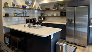 Une cuisine moderne dotée d’un  îlot central, d’appareils électroménagers en acier inoxydable et d’éléments décoratifs.