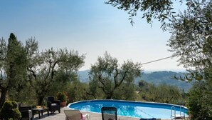 A swimming pool with a view of mountains, surrounded by trees and outdoor furniture. - Chantal by Interhome (Capannori)