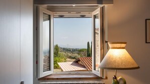 A room with a window overlooking a landscape, a radiator below the window, and a table with a lamp and a green vase. - Chantal by Interhome (Capannori)