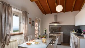 A modern kitchen with a large stove, a dining table with chairs, and a view of the outdoors through a window. - Chantal by Interhome (Capannori)