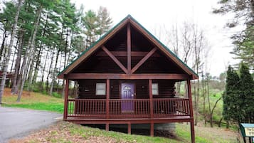A cabin with a front porch and a door, surrounded by trees.